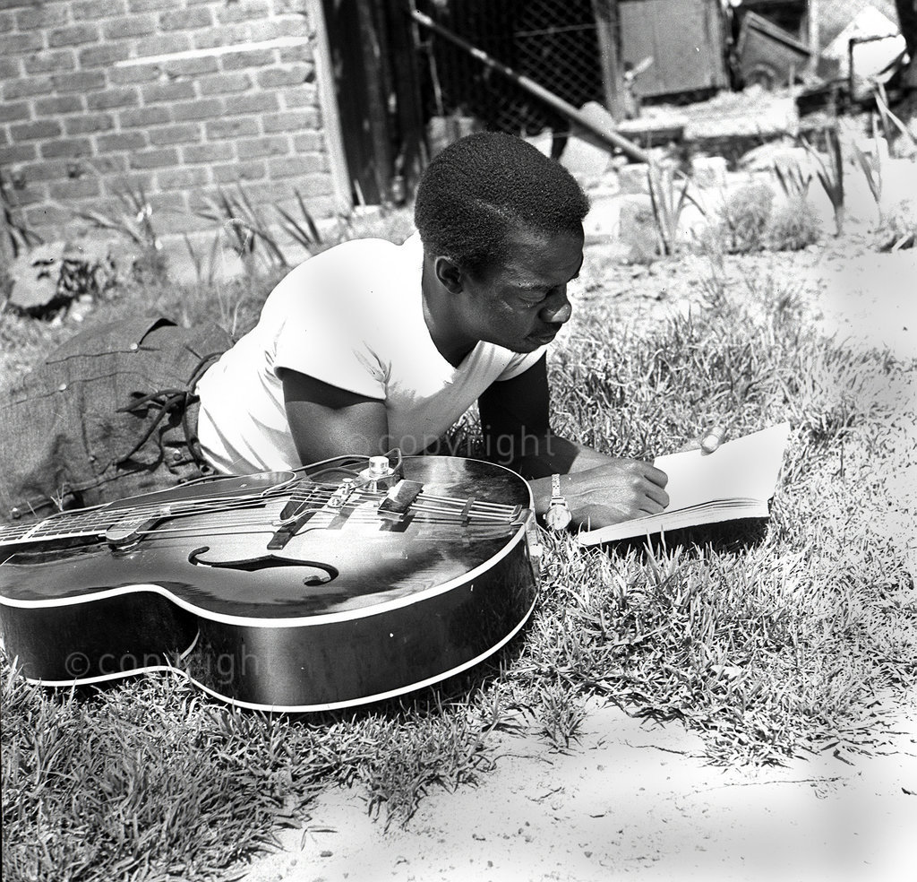 DM2000030608:SAED:MUSIC:PERSONALITY:FEB1952 - Meet The Music's General - Meet The Maestro - General 'Genie' Duze, the most genial of musicians. Together with Billy Roach they share the honour of being South Africa's top Guitarists. Genie has sat on nearly all the stages of the Union's leading towns. He has also taken part in a film. 'Genie' is a love of books and gets lots of ideas from even a simple folk tale. But book or no book the guiter must always be around. (Photograph by Jurgen Schaderberg  © Baileys Archives) 