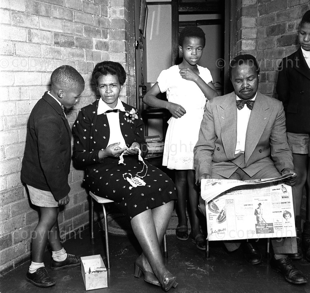 South Africa, 1955. Masterpiece In Bronze: Dan Twala. Family man, Daddy Dan with his brilliant wife Regina, BA in Social Science, and son Vusimuzi, with a friend. Few people in South Africa are so well known as Daniel Reuben Twala. From Cape Town to Johannesburg his name is legend. To the sports fans he is 'Master Sport': to Society he is the 'Man Who Gets Things Done': to the Johannesburg City Council he is the manager of the Johannesburg Bantu Sports Club, one of the most important executive positions in the country.