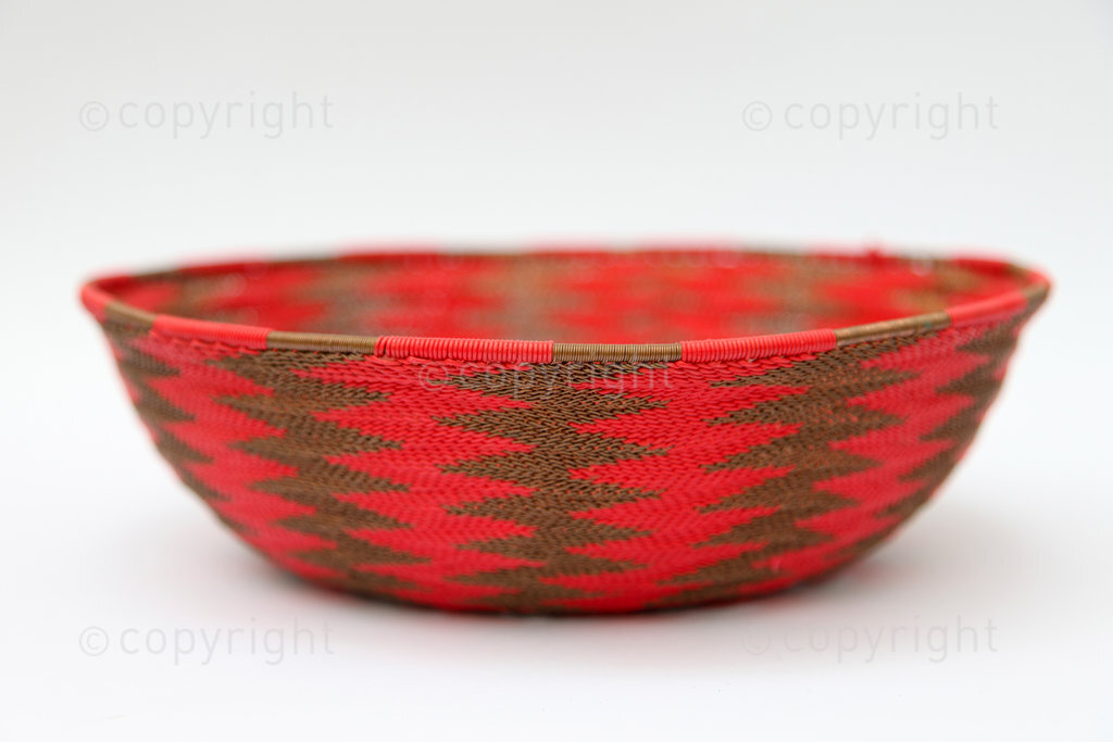 An Imbenge basket made from telephone wire.  This Imbenge was made in the Msinga area of KwaZulu-Natal in the early 1990s. There is a long rural traditional Zulu practice of making Imbenge baskets from natural materials for use as beer pot covers. Various types of grasses, the bark of the wild banana, and the Ilala Palm are used to weave the baskets. In urban areas Zulu night watchman and miners began weaving Imbenge from scraps of wire.