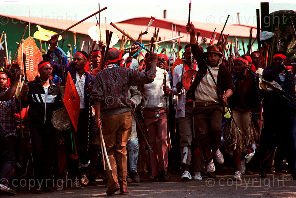 IPMG0286 South Africa, Thokoza, 1990.
Inkatha Freedom Party hostel residents storm out of a hostel on Thokoza's Khumalo street in the traditional impi formation, in this township east of Johannesburg. Thousands of people, both civilians and combatants died in the so-called Hostel War from 1989-1995.
Photograph by Greg Marinovich/South Photographs