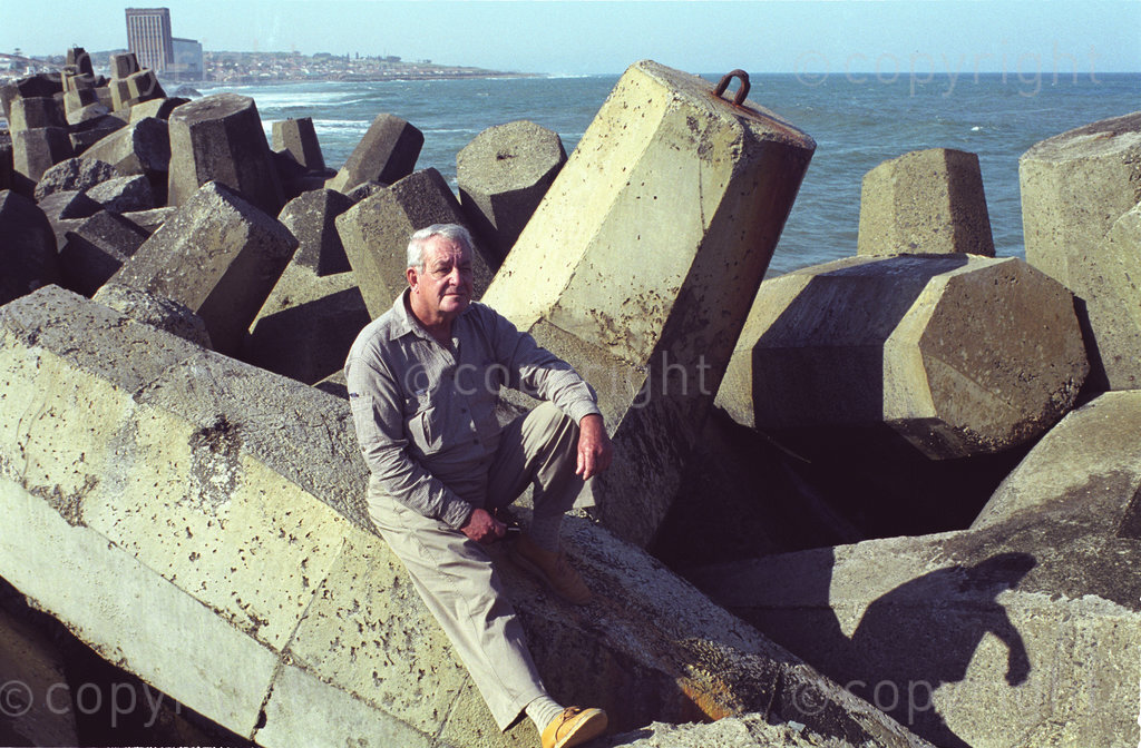 DG0026, South Africa, East London, circa 1999: 

Aubrey Kruger, who built the first dolos from pieces of broomstick, sits among the products of his idea, each of them weighing 17 tons on breakwater at East London. It was here that this system of interlocking concrete 