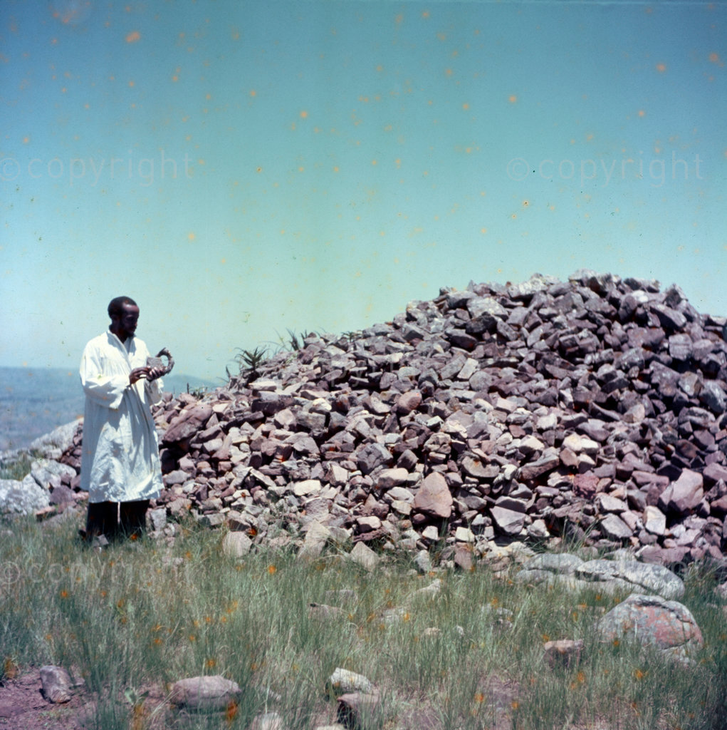 Amos Shembe shows the cairn of stones made by pilgrims. Each stone represents one completed pilgrimage by one person. Stones are placed on this cairn on the last day of the convention together with grass head- ring, (as held by Amos Shembe).