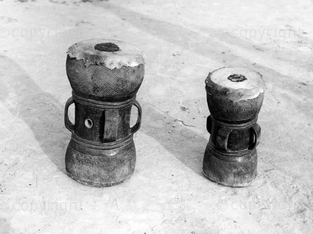 One group of Chokwe lived on the left bank of the Kasai river and the other in the area surrounding Dilolo. These Mikupela hour glass drums are from the Dilolo area, Lualaba district, Katanga Province. The mukupela drum was used in the past on royal occasions, e.g. for announcing wars. Nowadays it is a dance drum played sitting down. They are buzzing drums with a mirliton, played both ends. One side deep (has wax), the other higher. See article by Marie-Louise Bastin, Musical instruments, songs and dances of the chokwe, in journal, African music, vol 7. no.2, 1992.