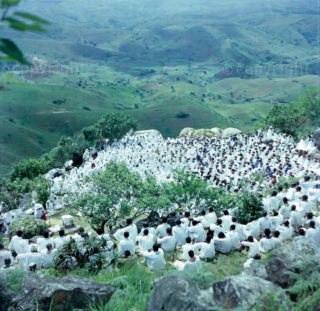 Closer view of the Shembe Church service. In the foreground are the men and boys; in the middle distance are married women distinguished by their red head- dresses. On the far side are unmarried girls each with a white cloth over the head.