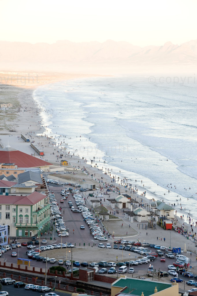 Muizenberg beach as seen from Boyes Drive during the December holidays. Muizenberg beach is a popular tourist attraction in Cape Town is visited by thousands of people every year. Muizenberg is a beach-side suburb of Cape Town, South Africa. It is situated where the shore of the Cape Peninsula curves round to the east on the False Bay coast. It is considered to be the birthplace of surfing in South Africa and it is home to the African Institute for Mathematical Sciences. Muizenberg has a fine, long beach that in effect stretches all the way round the top of False Bay to the Strand, a distance of over 20 km. False Bay, known for its population of White Sharks, also has a shark watch service that operates from Muizenberg, signalling alerts when sharks come in proximity of bathers and surfers. Above Muizenberg there is a line of steep cliffs that is very popular as a venue for rock climbing. However, certain parts of the cliff are off-limits to climbers when birds nest on the ledges. Historically, the village has several special features, including Het Posthuys (the Post House), Rhodes' Cottage and the site of the Battle of Muizenberg. Rhodes' Cottage is a small house on the seafront that Cecil John Rhodes bought as a holiday cottage and this was where he died in 1902. The house is preserved as a museum dedicated to Rhodes' life and is open to the public.
