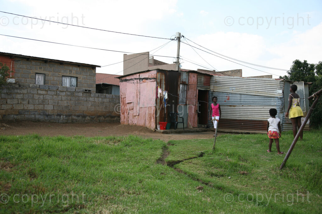 Young African girls outside a tin shack in a rural settlement