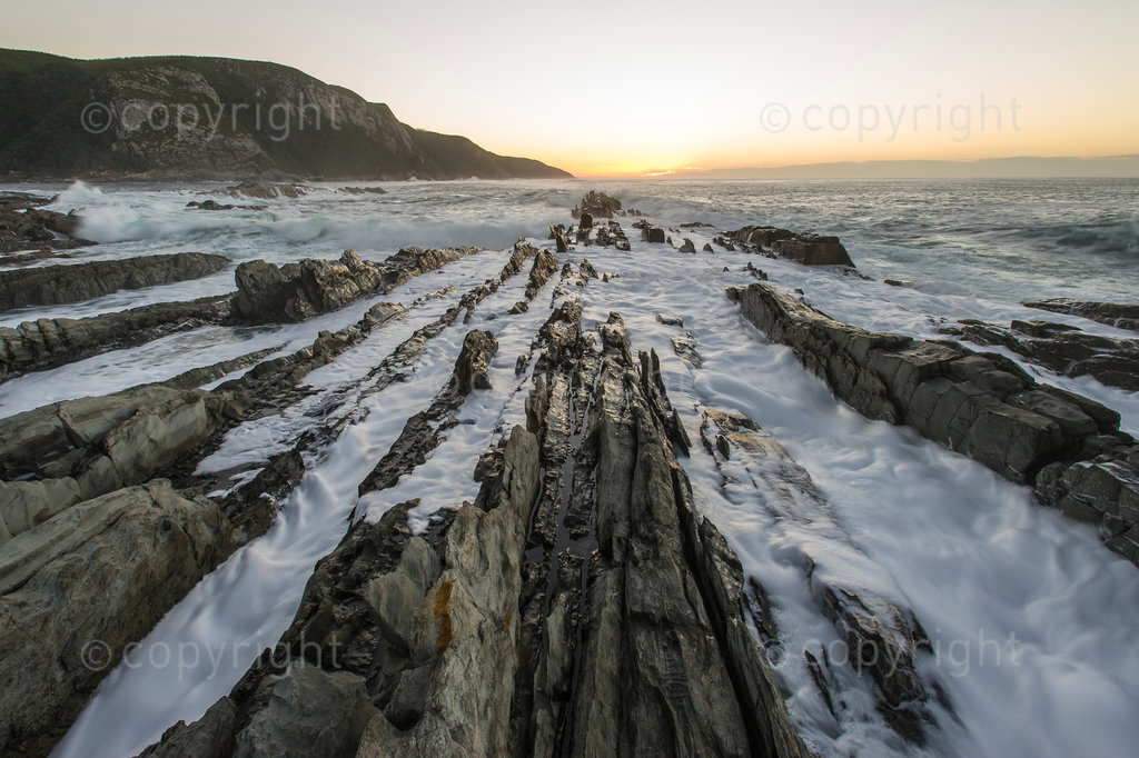 Gentle waves breaking over coastal rocks at dawn over the Tsitsikamma Marine Protected Area; Garden Route National Park; Western Cape; South Africa