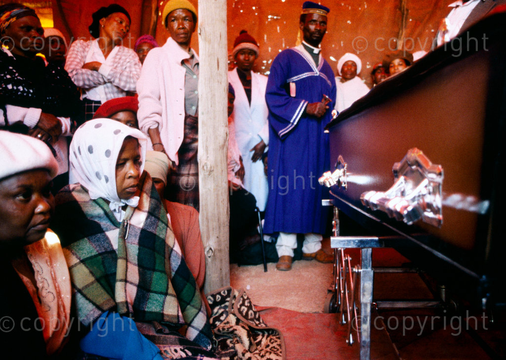 South Africa, 1987-1994. Family and friends gather to grieve around a coffin. 
Photo Credit: Ken Oosterbroek / african.pictures Photo Credit: Ken Oosterbroek / african.pictures