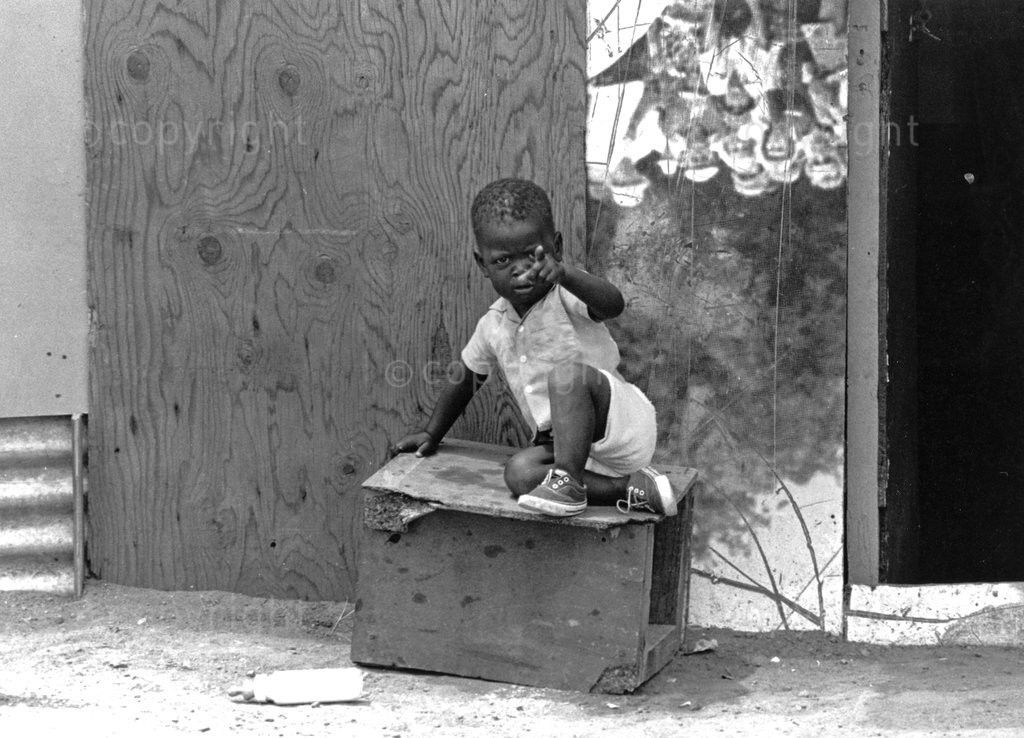 A child outside his home in Soweto, 1993.

Ruth Seopedi Motau was the first black female photographer who was employed by a South African newspaper as photo editor. Her photography focuses on social documentary influenced by photojournalism and the marginalisation of black people and communities.