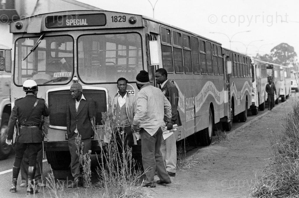 July 3, 1980. Putco bus drivers' strike. Traffic officer confronts strikers, near rows of empty buses.  Photo by Robert Tshabalala. Â© Times Media