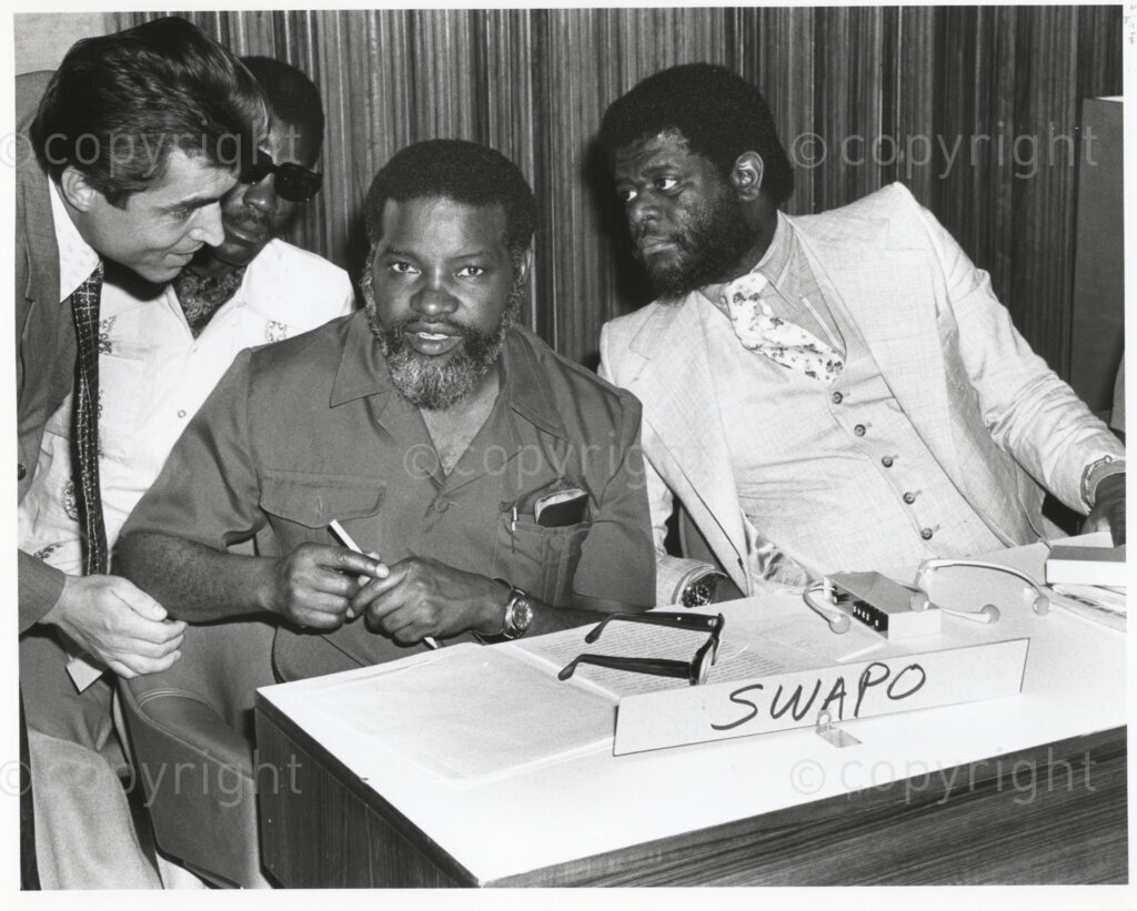 Lagos, Nigeria, 19770822. PHOTO: ANC Archives.

At the “World Conference for Action against Apartheid”, in Lagos, Nigeria on 22 August 1977, Sam Nujoma (centre), President of the South West Africa People’s Organisation (SWAPO) and Theo-Ben Gurirab, SWAPO’s New York representative. This photograph forms part of a series of captioned photographic records titled “The United Nations and Apartheid”, that was presented to Nelson Mandela, President of the Republic of South Africa, by United Nations Secretary-General Boutros Boutros-Ghali in October 1994.