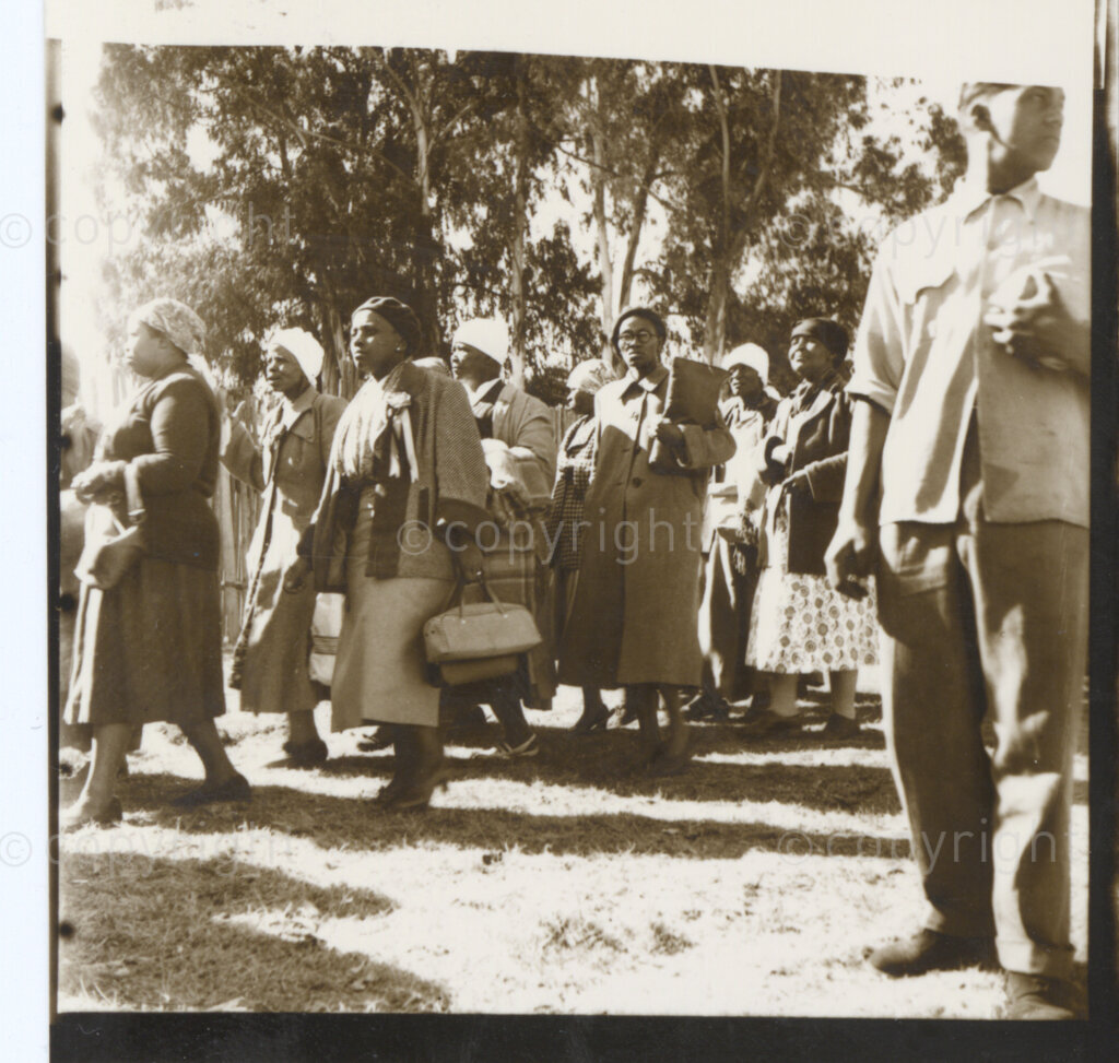 Kliptown, Johannesburg, Transvaal (now Gauteng), South Africa, 19550625. PHOTO: Eli Weinberg.
A group of women walk by a row of trees carrying bags. They may be delegates attending the Congress of the People held in Kliptown, Johannesburg on June 25 and 26th 1955. The Freedom Charter was adopted at this Congress.