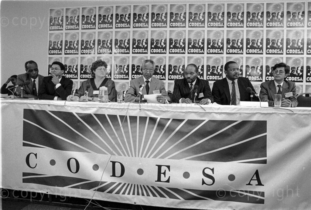 22 December 1992 - CODESA, L-R--Joe Nhlanla, Allan Boesak, Gill Marcus, Nelson Mandela, Jacob Zuma, Terror Lekota, and Valli Moosa. The first talks between ANC and Apartheid government towards the first free democratic elections. Convention for a Democratic South Africa (CODESA). A negotiating forum called CODESA was set up in 1991 after an agreement, the National Peace Accord, signed by the government and 18 other political organisations.
Photo by Eric Miller / african.pictures