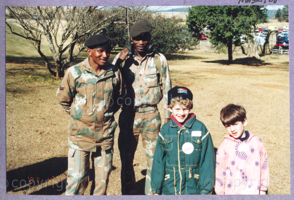 Hilton College, Pietermaritzburg, KwaZulu-Natal, South Africa, 19960717. PHOTO: ANC Archives.

Two young children stand with two SANDF (South African Defence Force) men in camouflage uniforms at the 78th birthday celebration of the President of South Africa, Nelson Mandela. More than 2,000 children who are living with disability in disadvantaged communities across the county have been invited to the day-long birthday extravaganza being held on the 17th July 1996 on the grounds of Hilton College near Pietermaritzburg in the KwaZulu-Natal Midlands. In advance of today's festivities, the invited children have been examined and treated by a team of orthopaedic specialists and physiotherapists. The event has the backing of the Nelson Mandela Children's Fund. Nelson Mandela was born on the 18th July 1918 in Mvezo, a small village in the Eastern Cape.