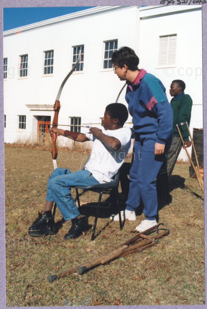 Hilton College, Pietermaritzburg, KwaZulu-Natal, South Africa, 19960717. PHOTO: ANC Archives.

A young disabled boy learns to use a bow and arrow at the 78th birthday party of the President of South Africa, Nelson Mandela, fondly known as Madiba. More than 2,000 children who are living with disability in disadvantaged communities across the county were invited to the day-long birthday extravaganza being held on the 17th July 1996 on the grounds of Hilton College near Pietermaritzburg in the KwaZulu-Natal Midlands. In advance of today's festivities, the invited children have been examined and treated by a team of orthopaedic specialists and physiotherapists. Many of them have been given life-changing wheelchairs. The event has the backing of the Nelson Mandela Children's Fund. Nelson Mandela was born on the 18th July 1918 in Mvezo, a small village in the Eastern Cape.