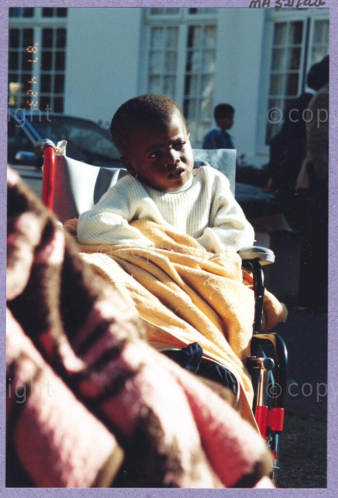 Hilton College, Pietermaritzburg, KwaZulu-Natal, South Africa, 19960717. PHOTO: ANC Archives.

A young child sits warmly wrapped in the new wheelchair that he has received at the 78th birthday celebration of the President of South Africa, Nelson Mandela. More than 2,000 children who are living with disability in disadvantaged communities across the county have been invited to the day-long birthday extravaganza being held on the 17th July 1996 on the grounds of Hilton College near Pietermaritzburg in the KwaZulu-Natal Midlands. In advance of today's festivities, the invited children have been examined and treated by a team of orthopaedic specialists and physiotherapists. Many of them have been given life-changing wheelchairs. The event has the backing of the Nelson Mandela Children's Fund. Nelson Mandela was born on the 18th July 1918 in Mvezo, a small village in the Eastern Cape.