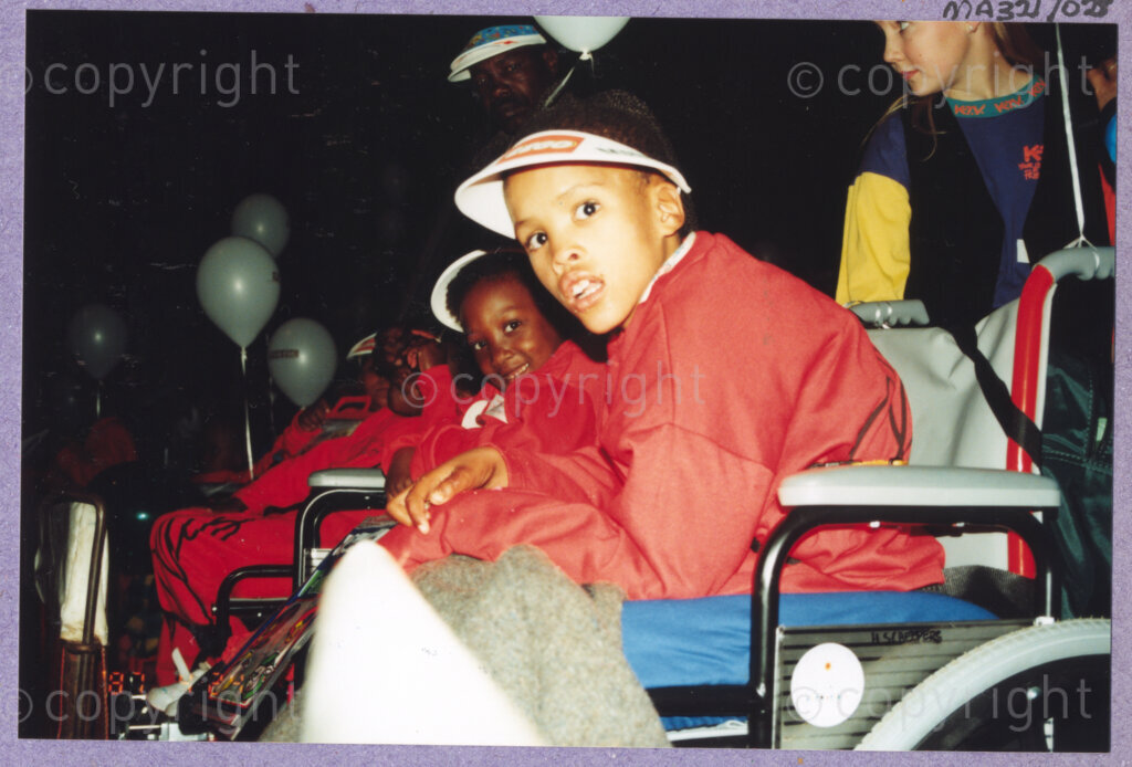 Hilton College, Pietermaritzburg, KwaZulu-Natal, South Africa, 19960717. PHOTO: ANC Archives.

Children, dressed in warm red outfits they have been given for the occasion, enjoy their new wheelchairs at the 78th birthday celebrations of the President of South Africa, Nelson Mandela. More than 2,000 children who are living with disability in disadvantaged communities across the county have been invited to attend the day-long birthday extravaganza being held on the 17th July 1996 on the grounds of Hilton College near Pietermaritzburg in the KwaZulu-Natal Midlands. In advance of today's festivities, the invited children have been examined and treated by a team of orthopaedic specialists and physiotherapists. Many of them have been given life-changing wheelchairs. The event has the backing of the Nelson Mandela Children's Fund. Nelson Mandela was born on the 18th July 1918 in Mvezo, a small village in the Eastern Cape.