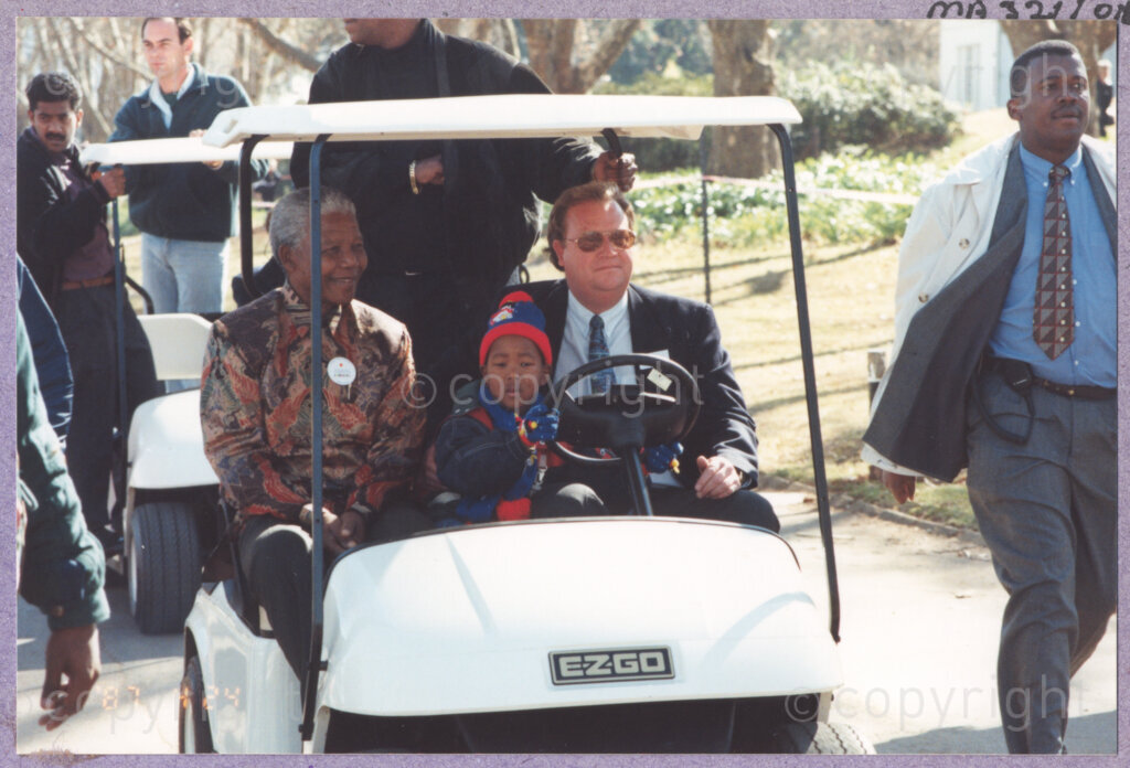 Hilton College, Pietermaritzburg, KwaZulu-Natal, South Africa, 19960717. PHOTO: ANC Archives.

The President of South Africa, Nelson Mandela, accompanied by his grandson, arrives at his 78th birthday extravaganza in a golf cart. The celebration is being held on the 17th July 1996 on the grounds of Hilton College near Pietermaritzburg in the KwaZulu-Natal Midlands. The cast of uMabatha, the Zulu Macbeth, escort him to meet his guests, namely the more than 2,000 children who are living with disability in disadvantaged communities from across the county. The event has the backing of the Nelson Mandela Children's Fund.