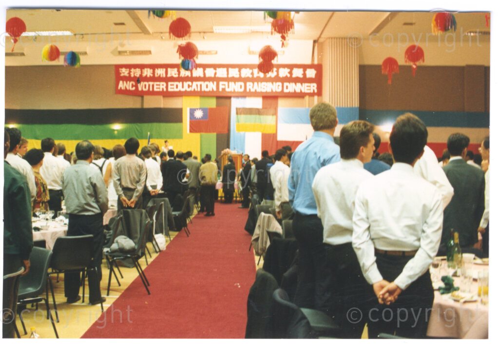 Parktonian Hotel, Johannesburg, Transvaal, South Africa, 19940309. PHOTO: ANC Archives.

Guests stand at the guest of honour, the President of the African National Congress (ANC), Nelson Mandela, enters the function room (which is decorated with Chinese lanterns). The Taiwanese community in South Africa is hosting an ANC voter education fund-raising dinner at the Parktonian Hotel on the 9 March 1994. Leading up to the 1994 elections in South Africa, Taiwan embarked on a public relations campaign in efforts to improve relations with the ANC, providing financial support to the ANC's election campaign. South Africa's diplomatic ties with Taiwan (The Republic of China) ended in 1998 however when Nelson Mandela, as President of South Africa, recognized the People's Republic of China.