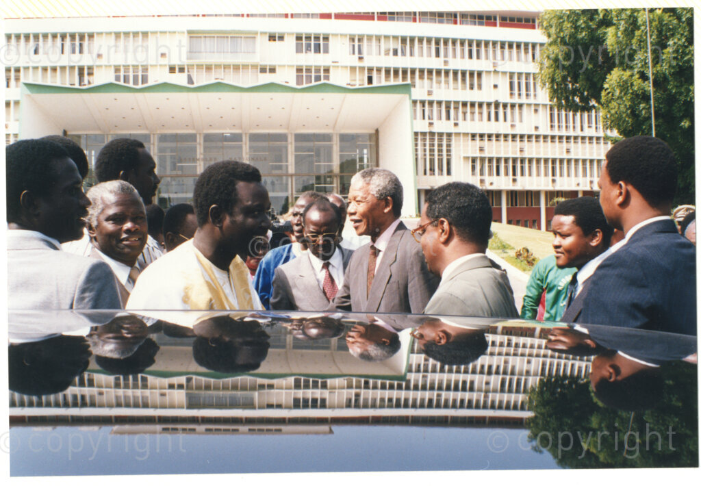 Senegal, 19920601. PHOTO: ANC Archives.

Nelson Mandela (forth from right) is standing next to a car with unidentified people during Mandela's visit to Senegal in June 1992.