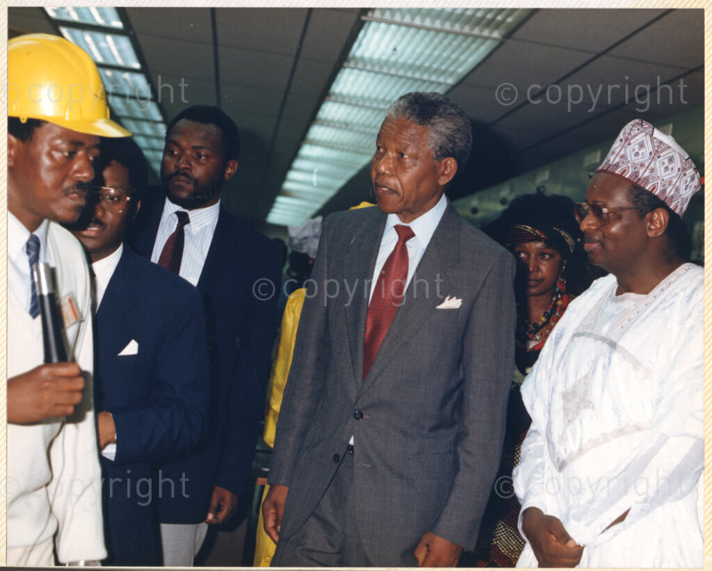 Kaduna Refinery, Kaduna, Kaduna, Nigeria, 19900515. PHOTO: ANC Archives.

Nelson Mandela (center), with Winnie Madikizela-Mandela behind him, listens to an official during his visit to Kaduna Refinery, Nigeria, 15 May 1990.