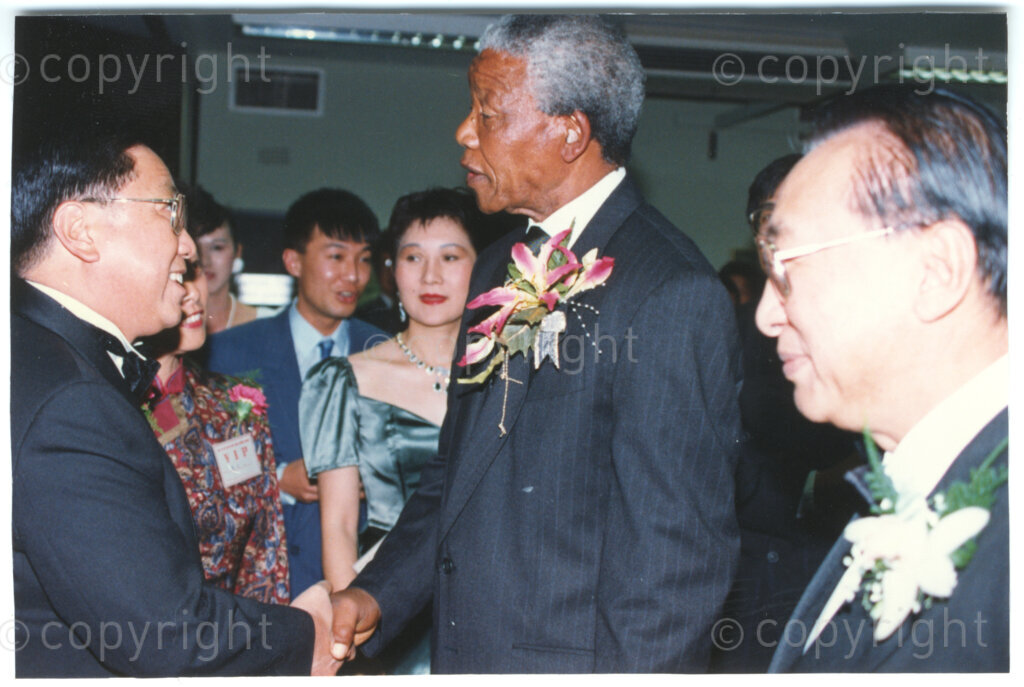 Parktonian Hotel, Johannesburg, Transvaal, South Africa, 19940309. PHOTO: ANC Archives.

The President of the African National Congress (ANC), Nelson Mandela (second right) wearing a large corsage shakes hands with one of his hosts at an ANC voter education fund-raising dinner hosted by the Taiwanese community in South Africa on the 9 March 1994. Leading up to the 1994 elections in South Africa, Taiwan embarked on a public relations campaign in efforts to improve relations with the ANC, providing financial support to the ANC's election campaign. South Africa's diplomatic ties with Taiwan (The Republic of China) ended in 1998 however when Nelson Mandela, as President of South Africa, recognized the People's Republic of China.