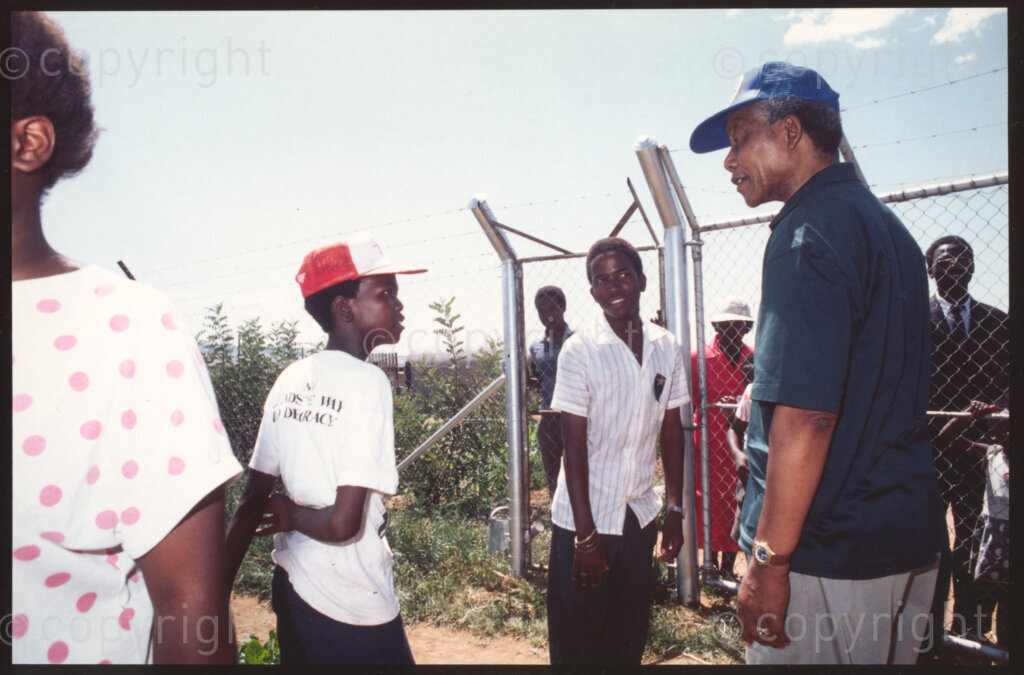 Jane Furse Agricultural Centre, Jane Furse, Transvaal, South Africa, 19921130. PHOTO: ANC Archives.

The President of the African National Congress (ANC), Nelson Mandela (right) talks to children at Operation Hunger's Jane Furse Agricultural Centre in the town of Jane Furse, Sekhukhuneland in November 1992.