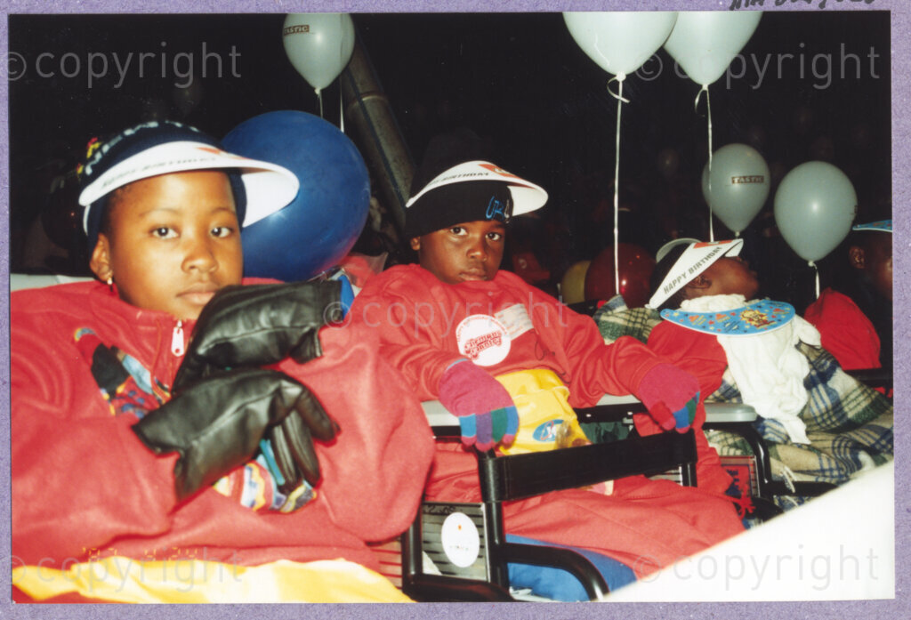 Hilton College, Pietermaritzburg, KwaZulu-Natal, South Africa, 19960717. PHOTO: ANC Archives.

Children, dressed in cosy, red outfits they have been given today sit in their wheelchairs at the 78th birthday celebration of the President of South Africa, Nelson Mandela. More than 2,000 children who are living with disability in disadvantaged communities across the county have been invited to the day-long birthday extravaganza being held on the 17th July 1996 on the grounds of Hilton College near Pietermaritzburg in the KwaZulu-Natal Midlands. The children, their carers, Madiba and other guests are being entertained playing games, enjoying party fare, and attending a circus performance in a big top (a first-time experience for Madiba who has, to date, never been to a circus!). The invited children have been examined and treated by a team of orthopaedic specialists and physiotherapists prior to the event and many of them have been given life-changing wheelchairs. The event has the backing of the Nelson Mandela Children's Fund.