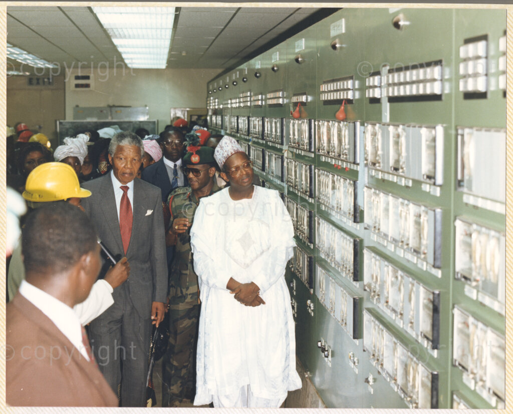 Kaduna Refinery, Kaduna, Kaduna, Nigeria, 19900515. PHOTO: ANC Archives.

Nelson Mandela (center) listens to an unidentified official during his tour of Kaduna Refinery, Nigeria, 15 May 1990.