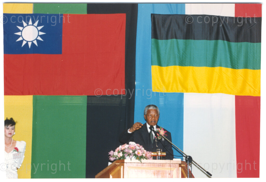 Parktonian Hotel, Johannesburg, Transvaal, South Africa, 19940309. PHOTO: ANC Archives.

With flags of the African National Congress (ANC) and the Republic of China (Taiwan) behind him, the President of the ANC, Nelson Mandela, speaks from the podium as the guest of honour at an ANC voter education fund-raising dinner hosted by the Taiwanese community in South Africa on the 9 March 1994. Leading up to the 1994 elections in South Africa, Taiwan embarked on a public relations campaign in efforts to improve relations with the ANC, providing financial support to the ANC's election campaign. South Africa's diplomatic ties with Taiwan (The Republic of China) ended in 1998 however when Nelson Mandela, as President of South Africa, recognized the People's Republic of China.
