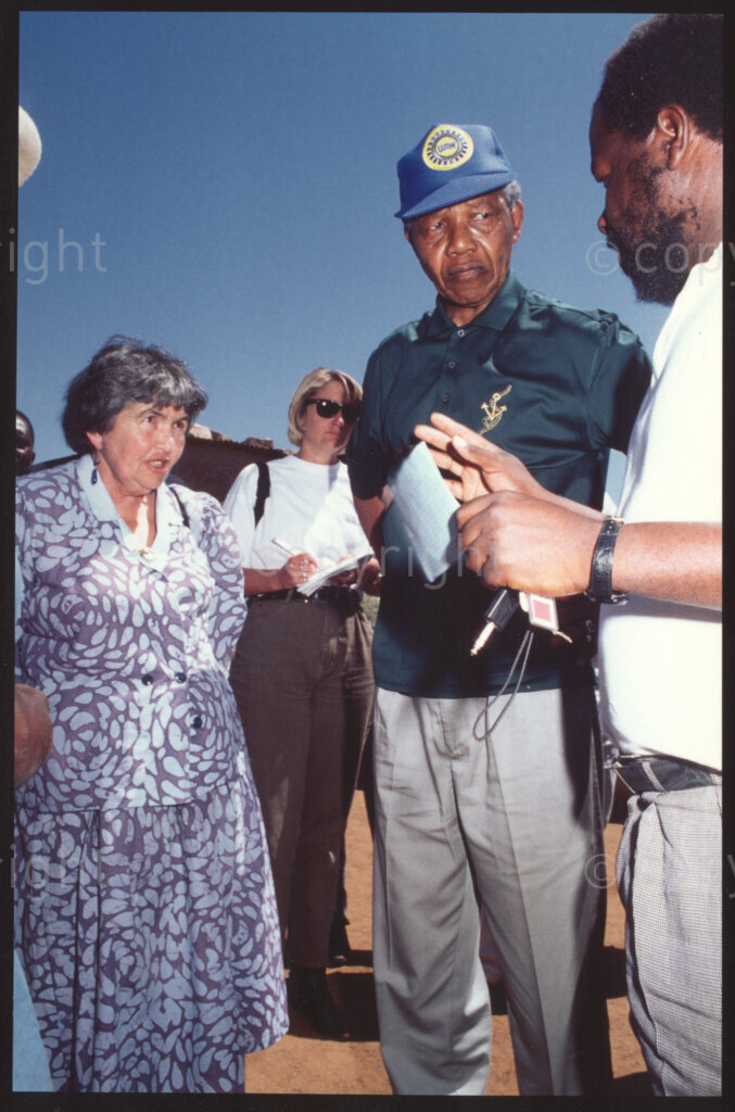 Tsehlwaneng village, Sekhukhuneland, Transvaal, South Africa, 19921130. PHOTO: ANC Archives.

Executive Director of Operation Hunger, Ina Perlman (left), and Nelson Mandela (centre), the President of the ANC, listen to Operation Hunger senior relief field worker Frans Themba (right) in Tsehlwaneng village in the Sekhukhuneland region.