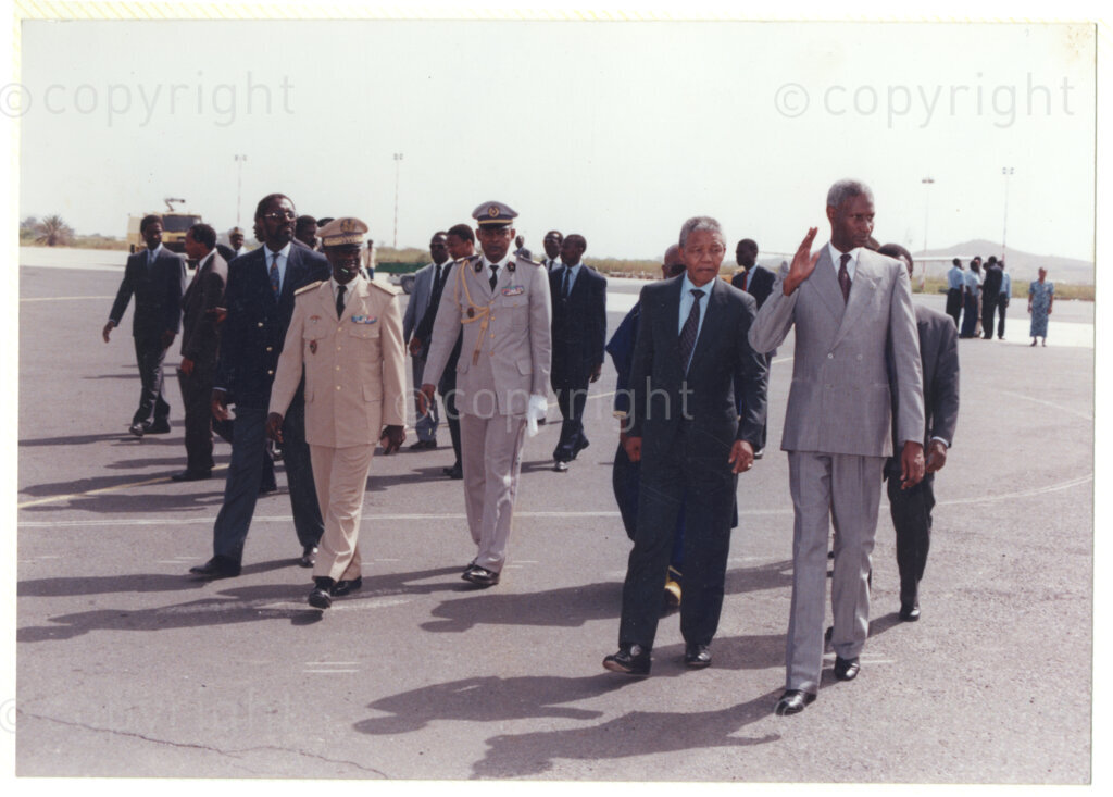 Senegal  , 19920601. PHOTO: ANC Archives.

Nelson Mandela (second from left) walking with Senegalese President, Abdou Diouf (tall man on the right), accompanied by men in uniform on what looks like an airport runway during his official visit to Senegal on 28 June 1992.