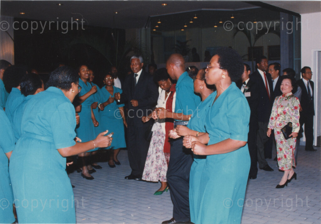 Parktonian Hotel, Johannesburg, Transvaal, South Africa, 19940309. PHOTO: ANC Archives.

The President of the African National Congress (ANC), Nelson Mandela (centre), dances with women wearing blue uniforms suggesting they are hotel staff at an ANC voter education fund-raising dinner hosted by the Taiwanese community in South Africa on the 9 March 1994. Leading up to the 1994 elections in South Africa, Taiwan embarked on a public relations campaign in efforts to improve relations with the ANC, providing financial support to the ANC's election campaign. South Africa's diplomatic ties with Taiwan (The Republic of China) ended in 1998 however when Nelson Mandela, as President of South Africa, recognized the People's Republic of China.