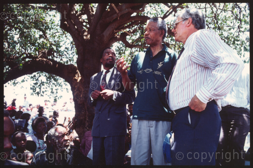 Maila Mapitsane village, Sekhukhuneland, Transvaal, South Africa, 19921130. PHOTO: ANC Archives.

The President of the African National Congress (ANC), Nelson Mandela (second right) with the Head of Group Public Affairs (Tiger Oats) Patrick McLaughlin (right in the striped shirt) in Maila Mapitsane village, Sekhukhunelande in November 1992.