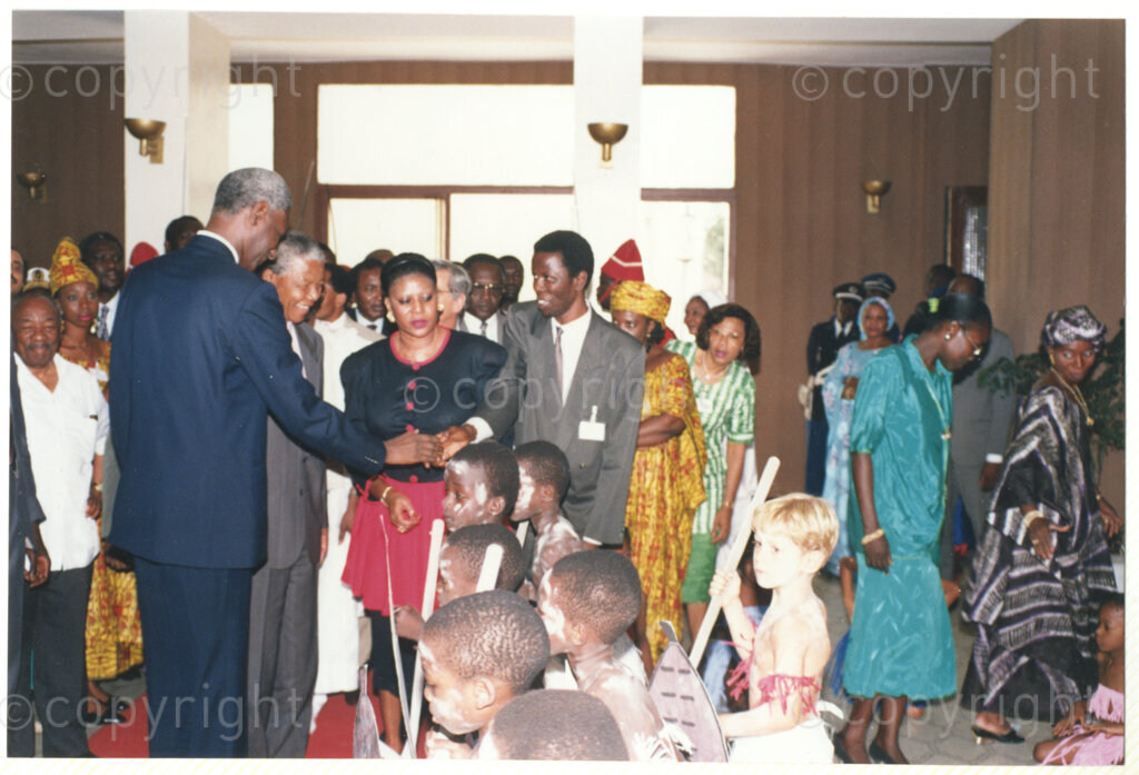 Senegal, 19920601. PHOTO: ANC Archives.

Nelson Mandela (second from left),standing next to Abdou Diouf (first from left), with Alfred Nzo (behind President Diouf, with the white shirt) is welcomed by an unidentified man and children in traditional wear, possibly during Mandela's official visit to Senegal in June 1992.