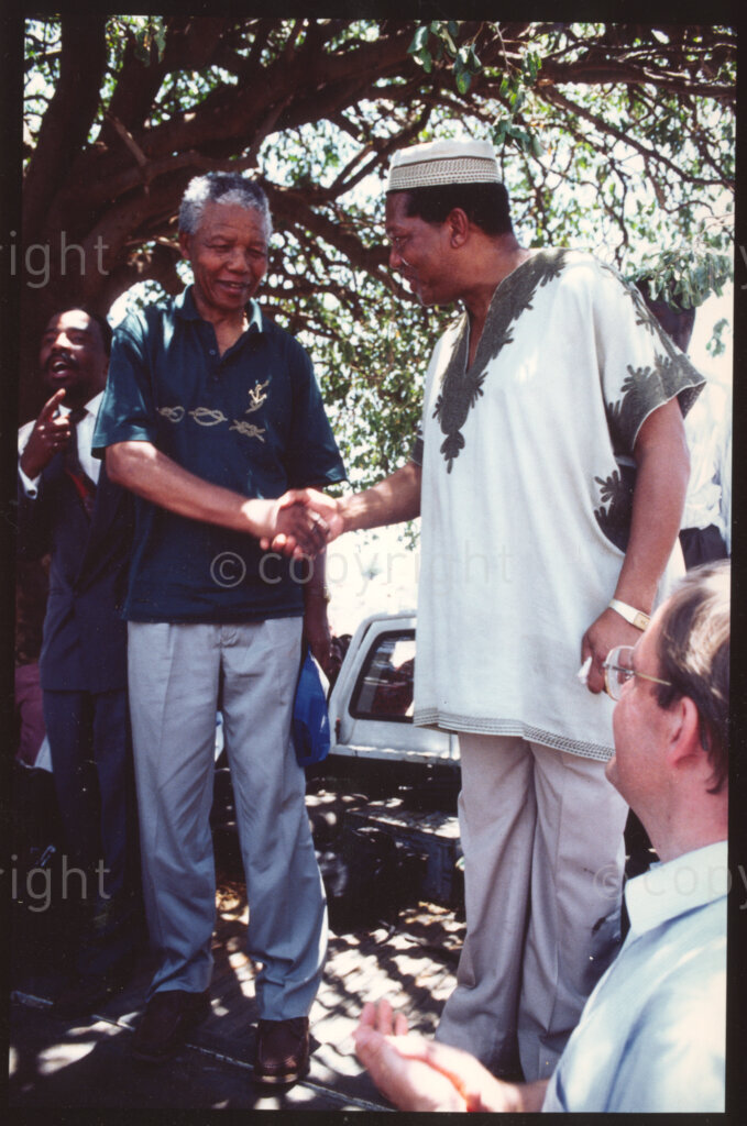 Maila Mapitane village, Sekhukhuneland, Transvaal, South Africa, 19921130. PHOTO: ANC Archives.

The President of the African National Congress (ANC), Nelson Mandela (left) and the Chairman of Operation Hunger, Michael Rantho (right) shake hands while standing on the back of an open truck on a visit to Maila Mapitane village, Sekhukhuneland, in November 1992.