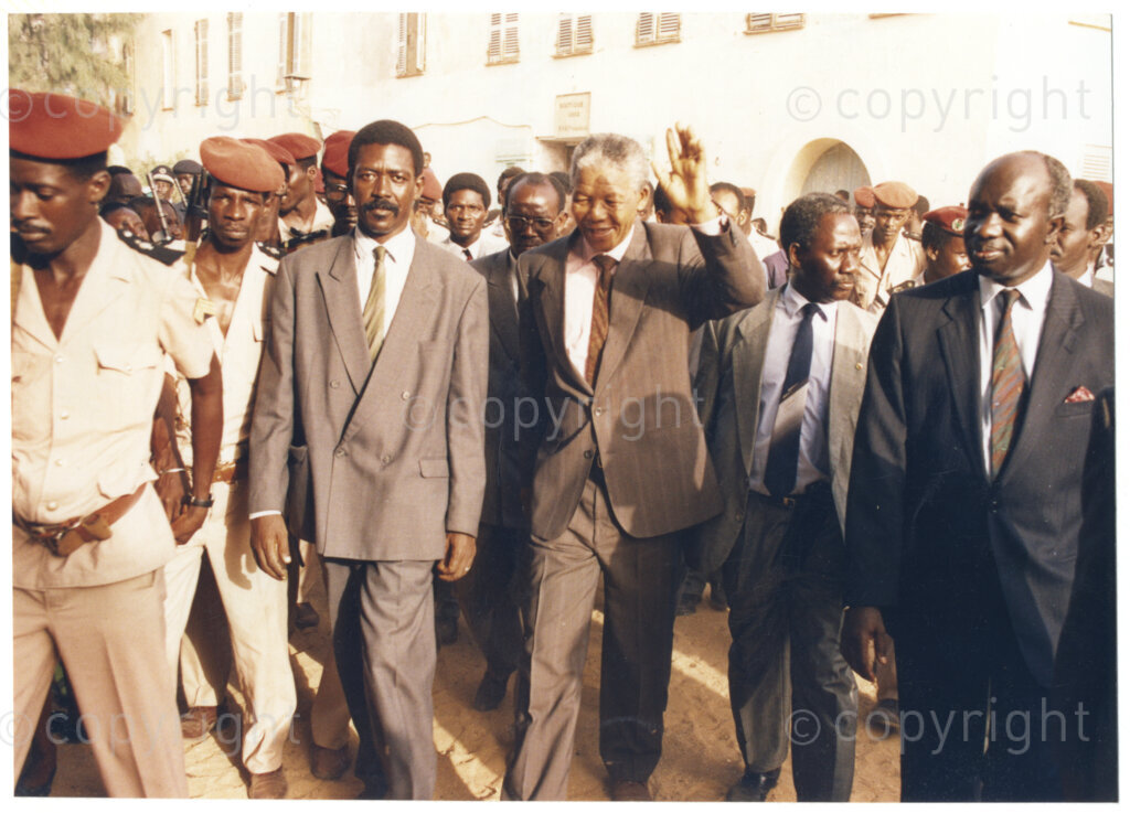 Senegal, 19920601. PHOTO: ANC Archives.

A photo of many people on a walkabout with Nelson Mandela (centre) waving at the crowd, during his visit to Senegal in June 1992.