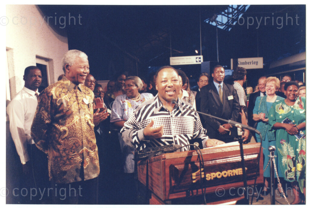 Kimberley Railway Station, Kimberley, Northern Cape, Republic of South Africa, 19970926. PHOTO: ANC Archives.

The new luxury Blue Train stops in Kimberley, Northern Cape on 26 September 1997 on its first journey from Pretoria to Cape Town after the relaunch, and dignitaries make speeches. Northern Cape Premier, Manne Dipico is at the microphone with President Nelson Mandela smiling on the left
