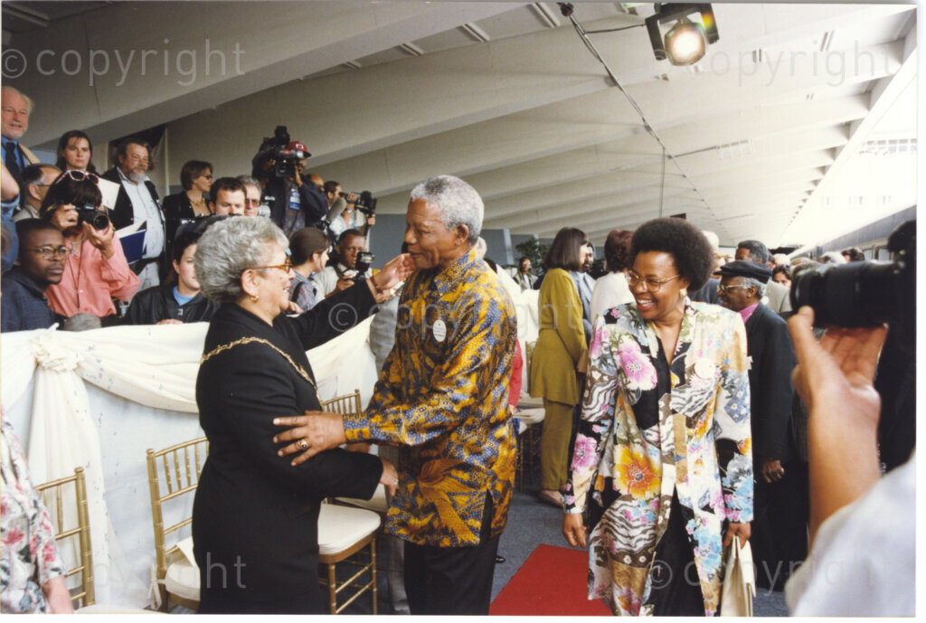 Cape Town Railway Station, Cape Town, Cape Province, Republic of South Africa, 19970927. PHOTO: ANC Archives.

President Nelson Mandela travels from Pretoria to Cape Town on the launch journey of the new Blue Train on 27 September 1997. He is accompanied by Graca Machel, (right) and several celebrities and dignitaries. He is seen here shaking the hand of Alderman Theresa Solomon on Cape Town Railway Station.