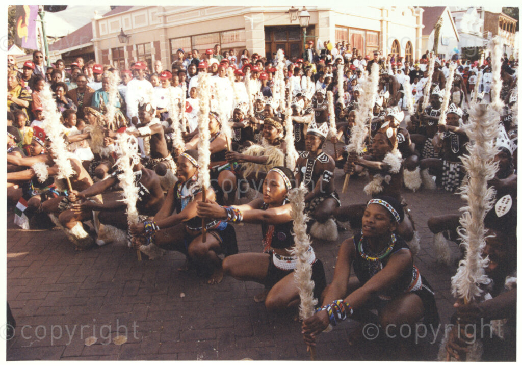 Gold Reef City, Johannesburg, Gauteng, South Africa, 19950717. PHOTO: ANC Archives.

Zulu dancers in traditional dress entertain the crowds at the 77th birthday celebration of the President of South Africa, Nelson Mandela, at Gold Reef City, Johannesburg, on Monday the 17th July 1995. More than 2,000 underprivileged children, including 34 children who are currently imprisoned, street children, children from orphanages, mentally disabled children and children who have been abused, have been invited to attend his birthday celebration with him. Nelson Mandela is attending this function in his personal capacity as he places special emphasis on the plight of children. A variety of entertainments have been put on for the children.
