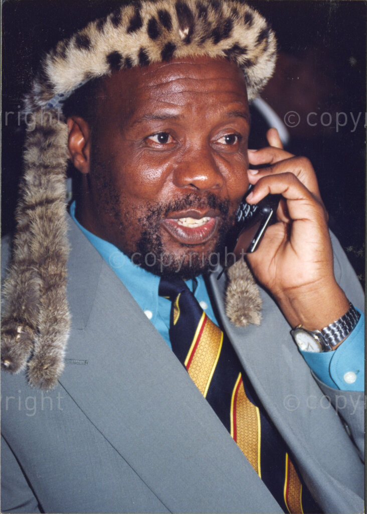 Cape Town, Western Cape, South Africa, 19970418. PHOTO: ANC Archives.

 A portrait of Nkosi Mpiyezintombi Mzimela, wearing a traditional Zulu animal skin headband (umqhele), and talking on a cell phone at the inauguration of the Council of Traditional Leaders on 18 April 1997 in Cape Town, Western Cape, South Africa.