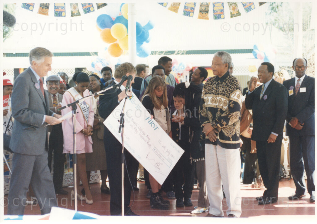 Gold Reef City, Johannesburg, Gauteng, South Africa, 19950717. PHOTO: ANC Archives.

The President of South Africa, Nelson Mandela, receives a donation towards the Nelson Mandela Children's Fund on the occasion of his 77th birthday celebration at Gold Reef City, Johannesburg, on Monday the 17th July 1995. Standing behind the other dignitaries is Miss South Africa (1994), Ms Basetsana Makgalemele (in pink). More than 2,000 underprivileged children, including 34 children who are currently imprisoned, street children, children from orphanages, mentally disabled children and children who have been abused, have been invited to attend his birthday celebration with him. Nelson Mandela is attending this function in his personal capacity as he places special emphasis on the plight of children. A number of similar donations to the Nelson Mandela Children's Fund have been by the private sector to mark the occasion. Nelson Mandela was born on the 18th July 1918 in Mvezo, a small village in the Eastern Cape.