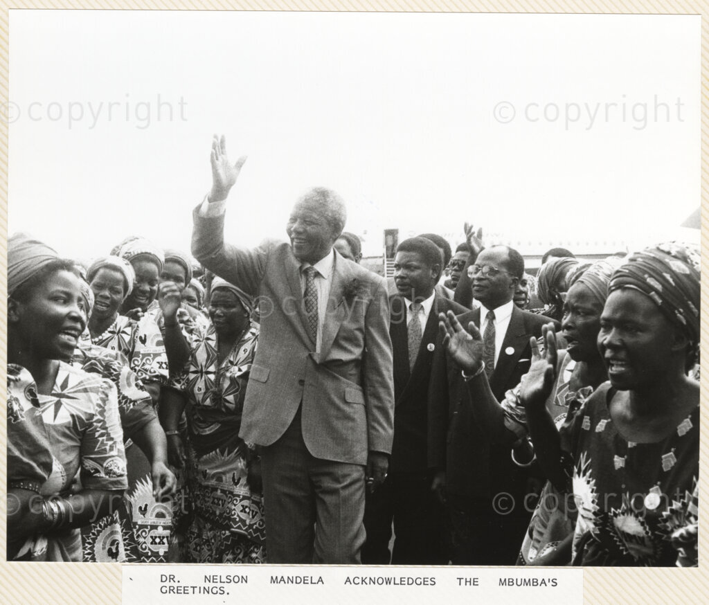 Chileka Airport , Blantyre, Blantyre District, Malawi, 19920617. PHOTO: ANC Archives.

Nelson Mandela (centre) waves to the assembled crowd on his arrival in Malawi on 17 June 1992. He is greeted at Chileka Airport by the Mbumba women in traditional dress. Walking beside Nelson Mandela is the Regional Chairman for the South, Dalton Katopola (second right) and the Minister of State in the President's Office, John (JZU) Tembo (right).