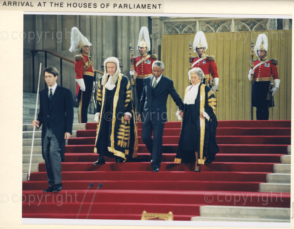 Houses of Parliament, London, United Kingdom, 19960701. PHOTO: ANC Archives: During his July 1996 state visit to the United Kingdom, President Nelson Mandela is invited to address a Joint Session of Parliament in Westminster Hall. Mandela is seen here amidst the pomp and pageantry. He is escorted into Westminster Hall, (wearing a dark suit), flanked by dignitaries.