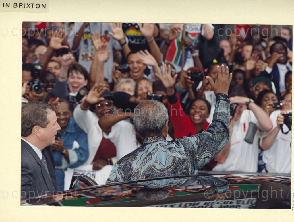 Brixton, London, United Kingdom, 19960701. PHOTO: ANC Archives: During his July 1996 state visit to the United Kingdom, (UK), crowds of admirers crammed the streets of London, to get a glimpse of President Nelson Mandela, the iconic South African philanthropist. Mandela, touched by their fervour, was warmly responsive.