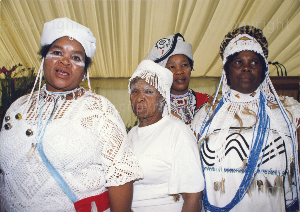 Cape Town, Western Cape, South Africa, 19970418. PHOTO: ANC Archives.

A group portrait of four women dressed in traditional Xhosa dress with Xhosa headdresses and beadwork at the Inauguration of the Council of Traditional Leaders in Cape Town, Western Cape, South Africa on 18 April 1997. All women are wearing predominantly white, the beadwork being mainly white and blue.