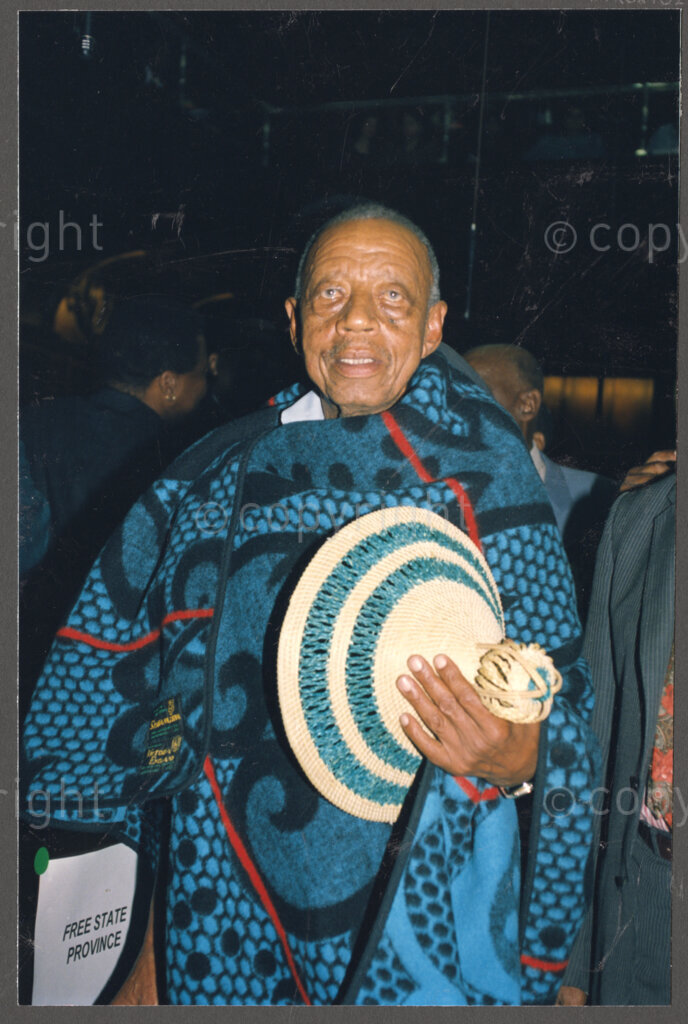 Cape Town, Western Cape, South Africa, 19970418. PHOTO: ANC Archives.

A portrait of an unidentified traditional leader wearing a blue and black blanket, the traditional attire of the Basotho, and holding his hat, at the inauguration of the Council of Traditional Leaders in Cape Town, Western Cape, South Africa on 18 April 1997.