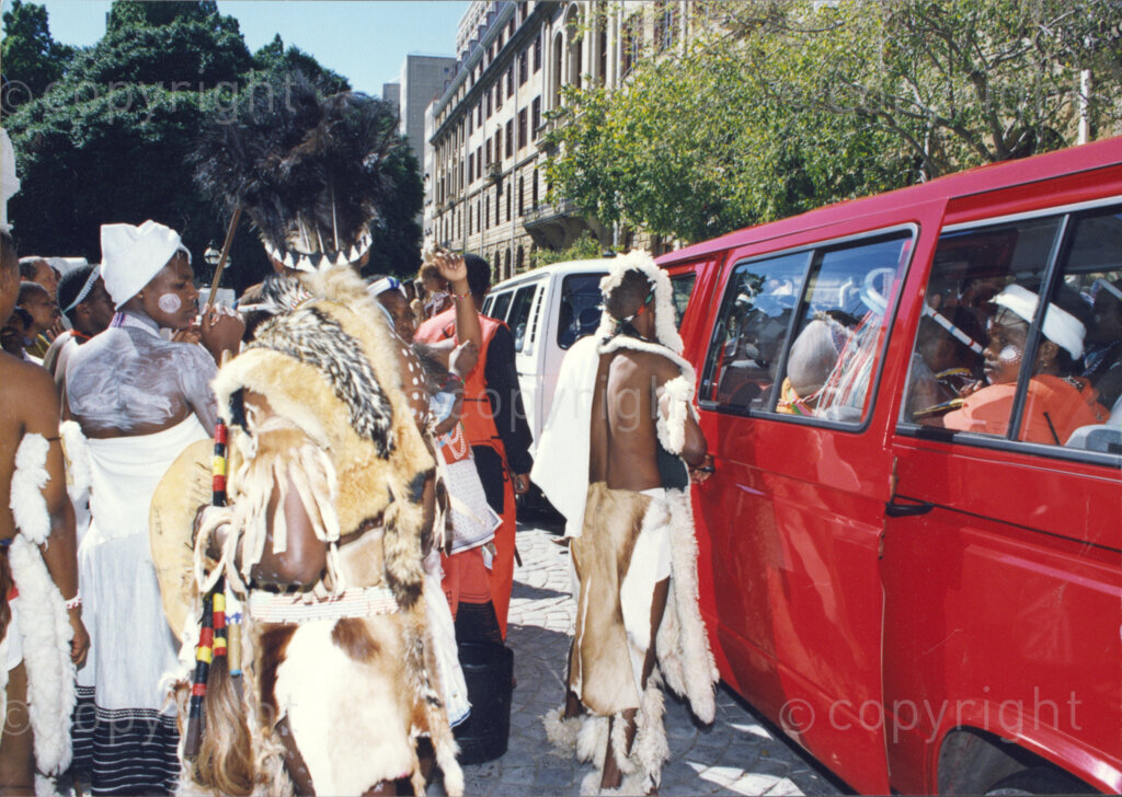 Cape Town, Western Cape, South Africa, 19970418. PHOTO: ANC Archives.

A group of men and women in traditional Zulu and Xhosa dress at the inauguration of the National Council of Traditional Leaders in Cape Town, Western Cape, South Africa on 18 April 1997. Several are standing on the road beside a red minibus taxi whilst others are seated in the taxi.