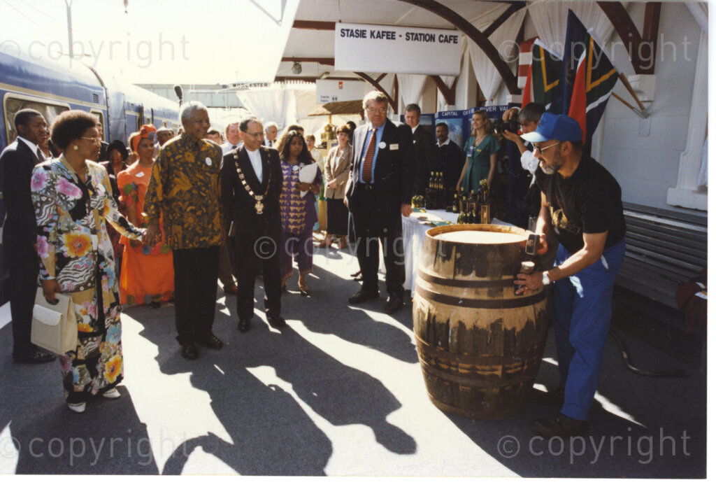Worcester Railway Station, Worcester, Western Cape, Republic of South Africa, 19970927. PHOTO: ANC Archives.

The new luxury Blue Train stops in Worcester, Western Cape on 27 September 1997 on its first journey from Pretoria to Cape Town after the relaunch. A local musician hammers out a tune on a wine barrel, for from left to right, Graca Machel, President Nelson Mandela and Councillor Riyahd Williams, Mayor of Worcester and other dignitaries.