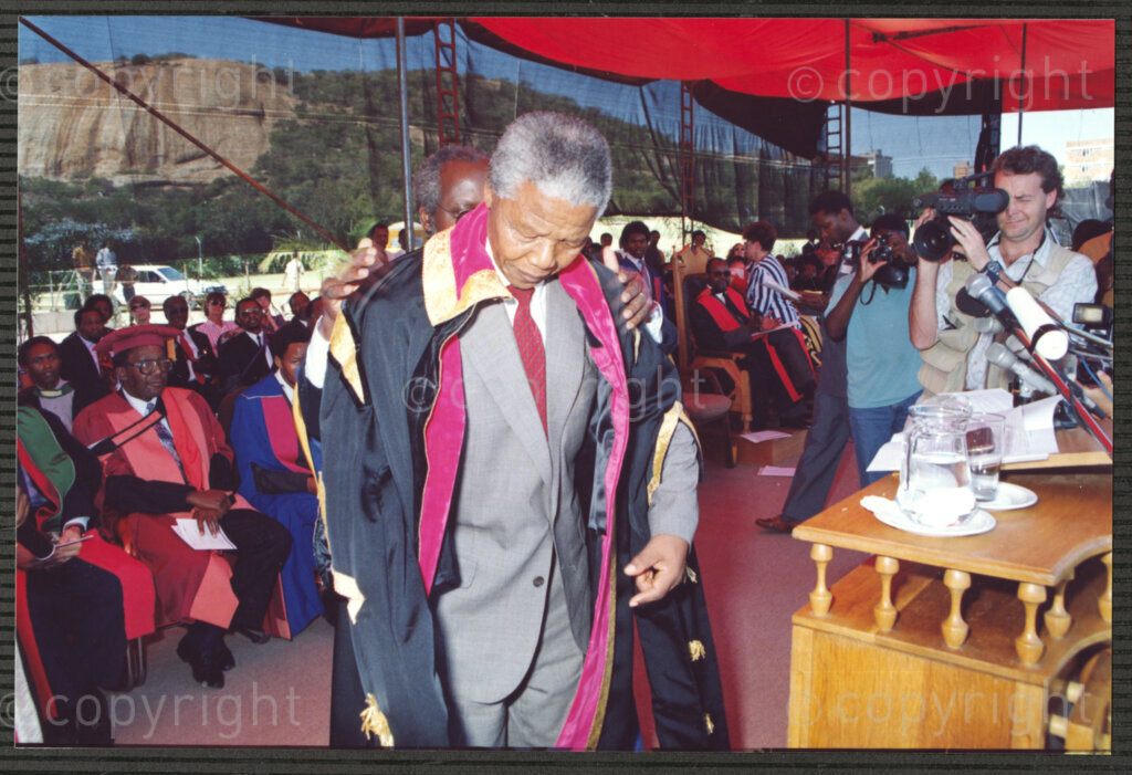 Turfloop Campus, University of the North, Mankweng, Northern Transvaal, South Africa, 19920425. PHOTO: ANC Archives.

Professor Walter Kamba, the chairman of the International Association of Universities and former vice chancellor of the University of Zimbabwe (just visible behind Nelson Mandela), formally installs Nelson Mandela, the president of the African National Congress (ANC), as the chancellor of the University of the North, 25 April 1992, Turfloop Campus of the University of the North (now the University of Limpopo), Mankweng, Northern Transvaal (now Limpopo), South Africa.
